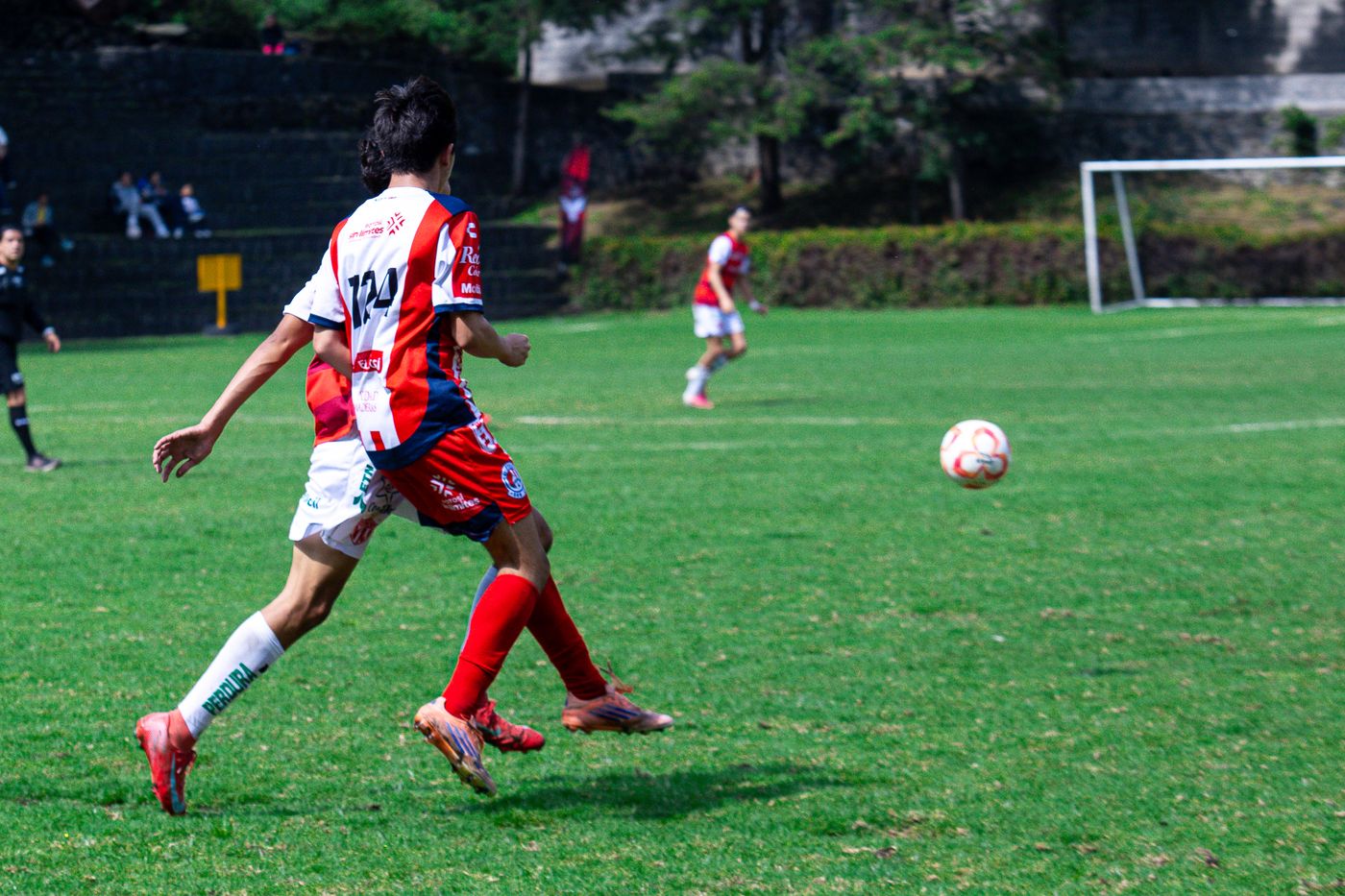 Jugador persiguiendo el balón suelto en la cancha