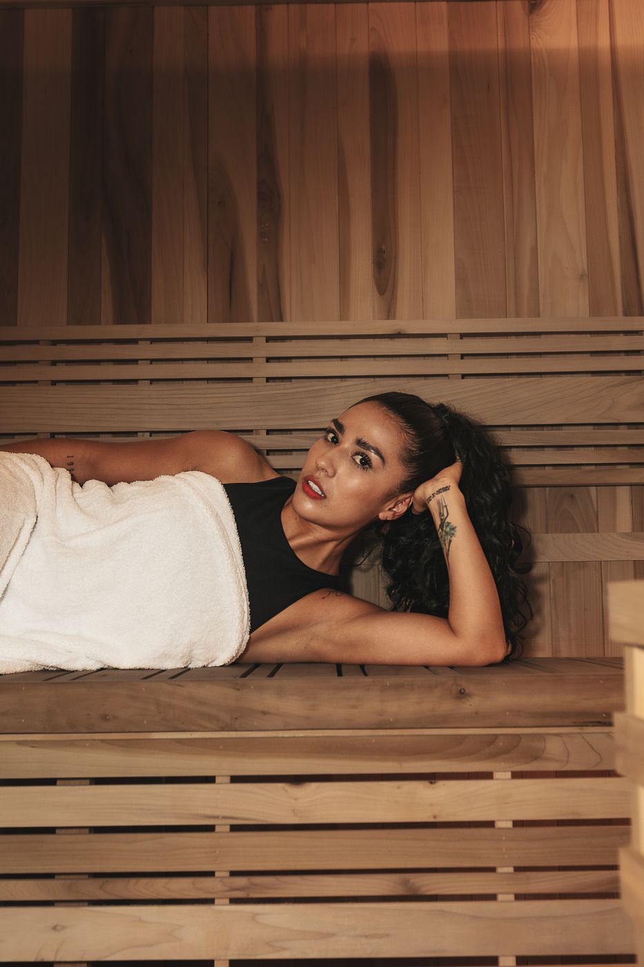 Mujer recostada sobre la banca de madera del sauna