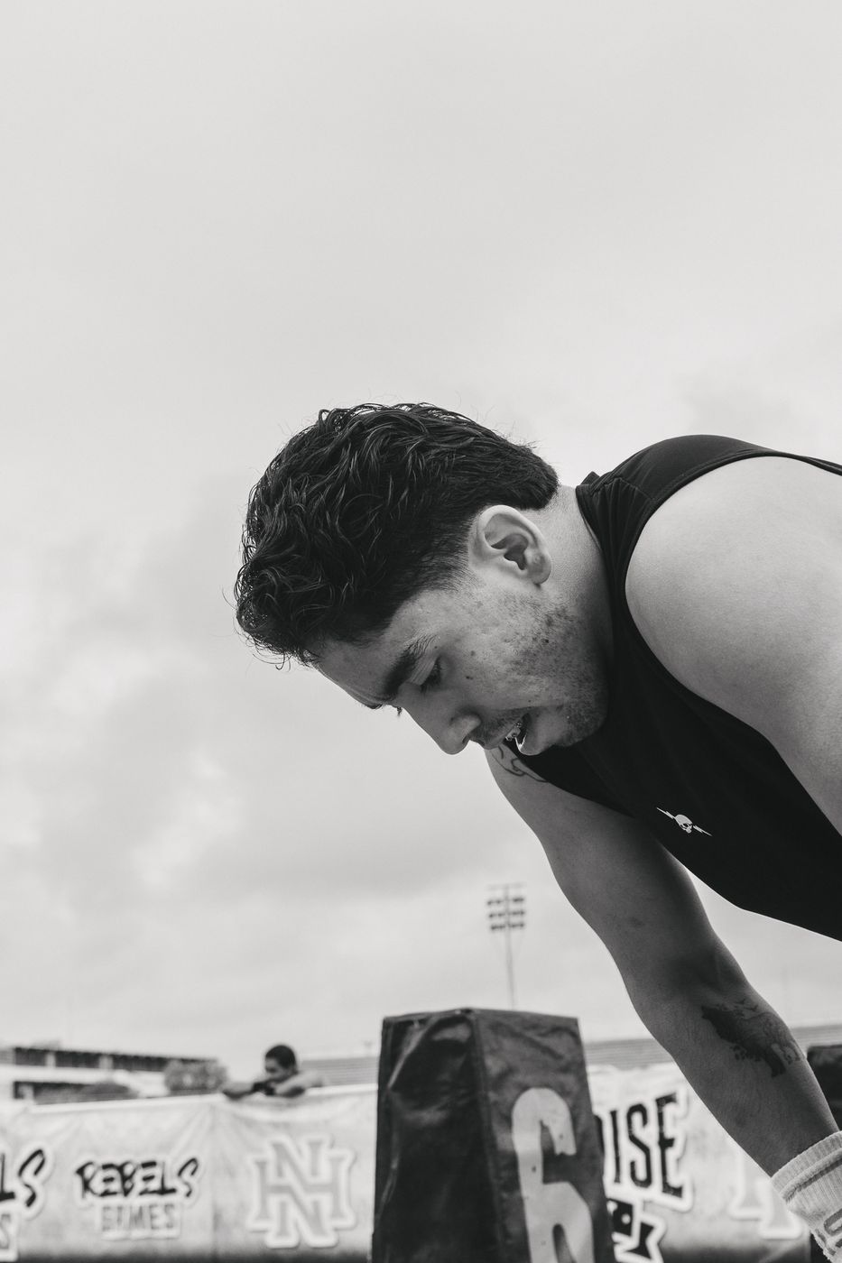 Atleta agotado inclinado sobre su cajón numerado, en blanco y negro