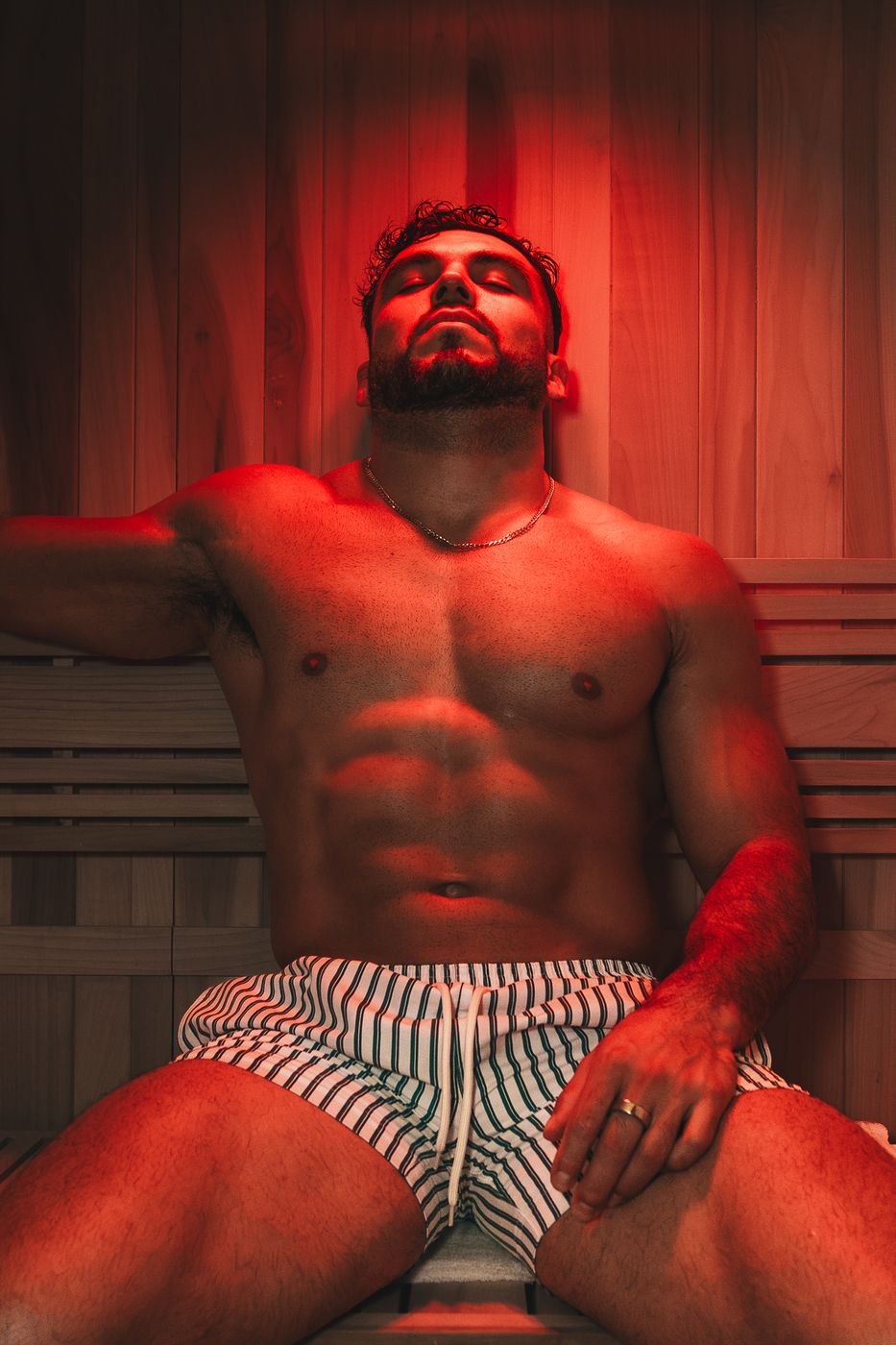 Hombre relajado en el sauna bajo luz roja, sesión para Alpha Recovery