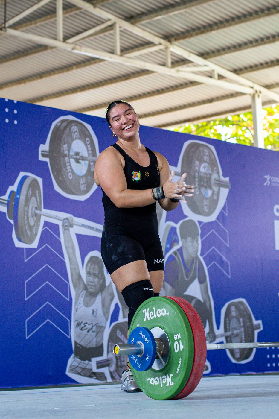 Atleta sonriendo junto a la barra cargada en competencia
