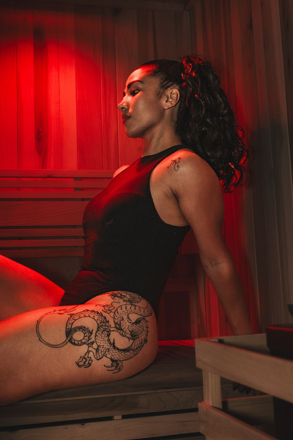 Mujer de perfil en el sauna iluminada con luz roja