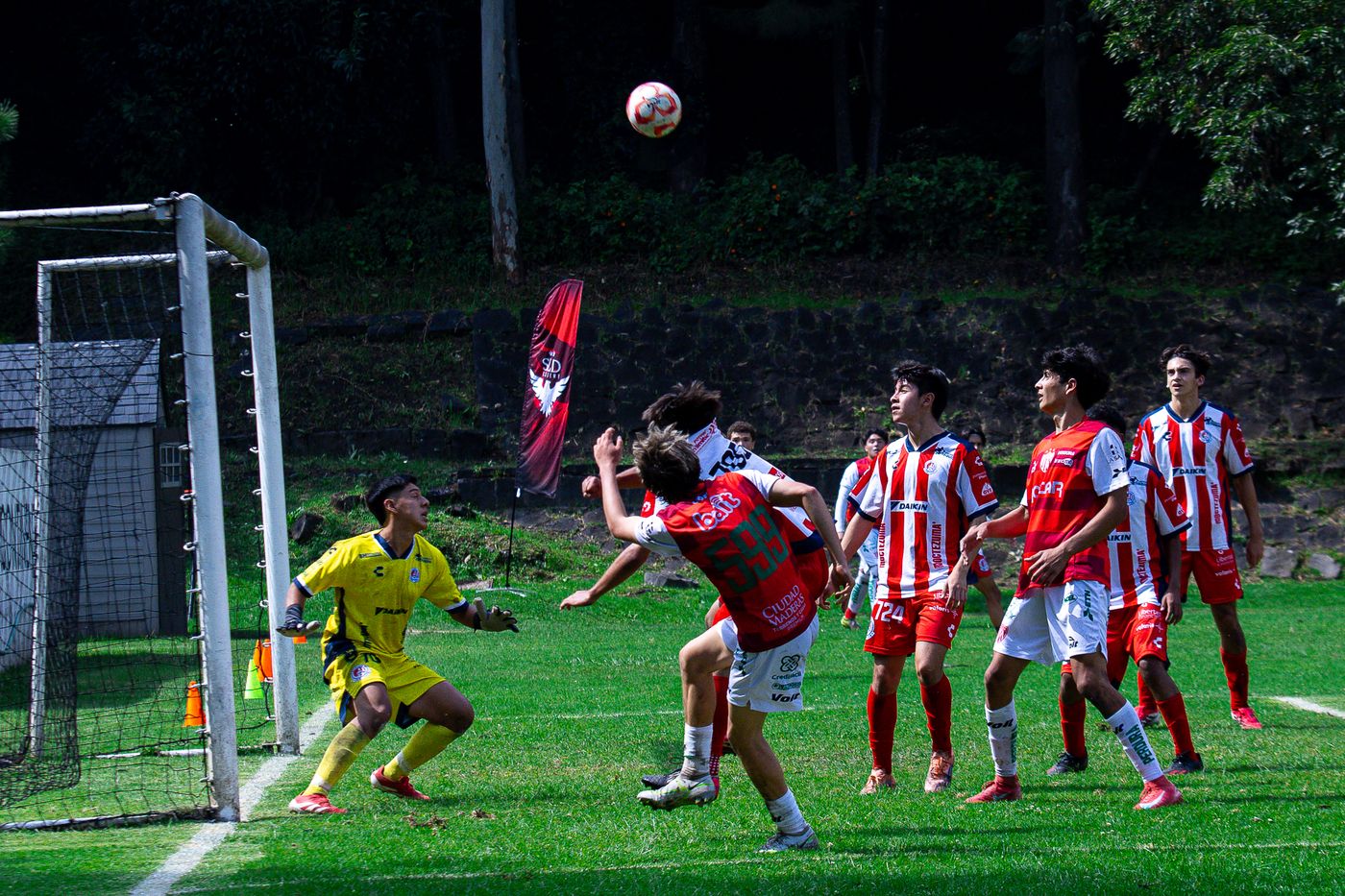 Jugador rematando de cabeza frente a la portería durante un tiro de esquina