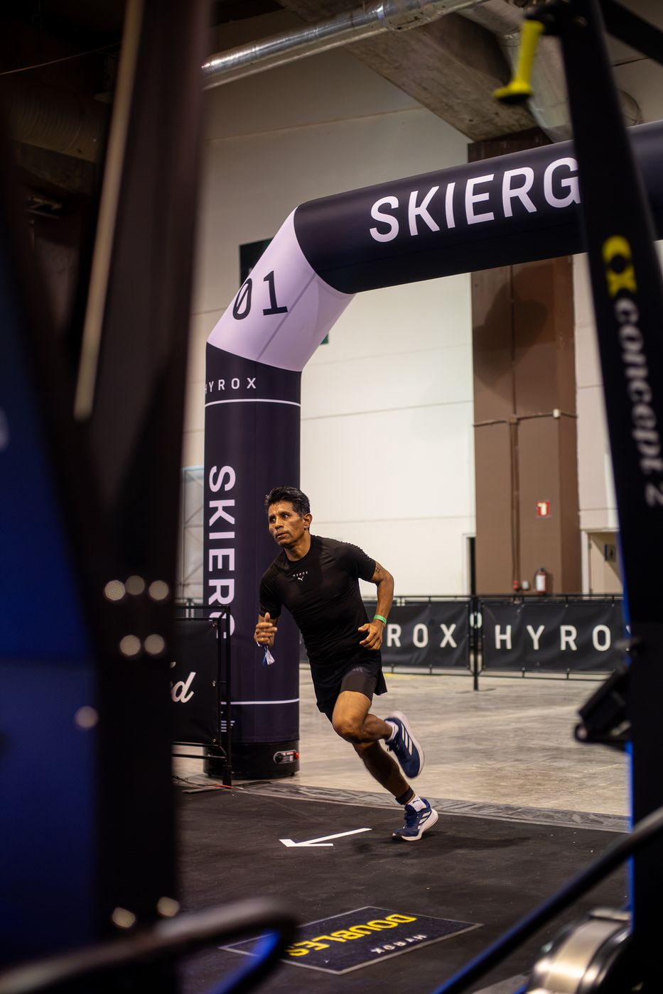 Atleta saliendo a toda velocidad bajo el arco de SkiErg en HYROX