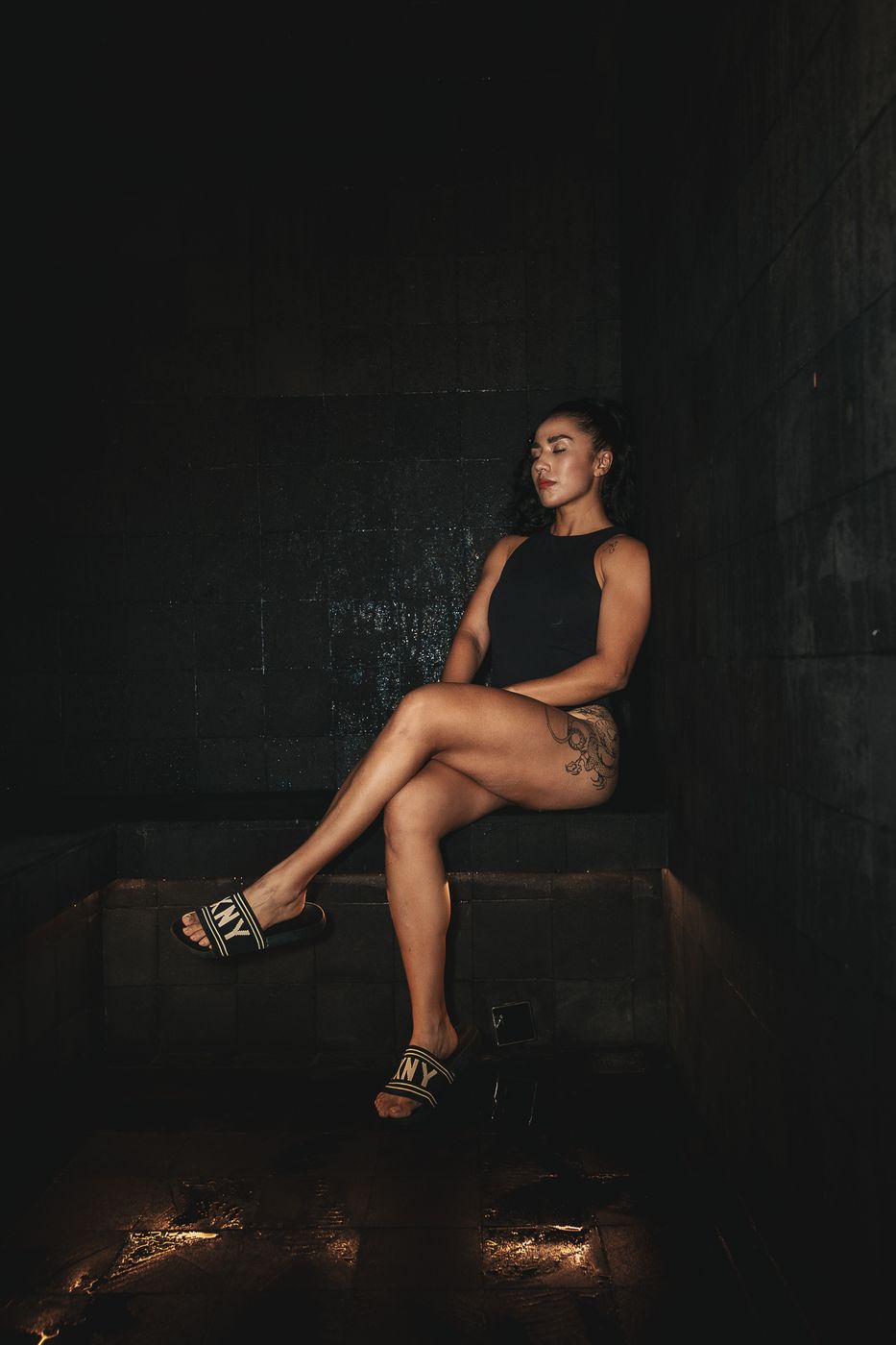 Mujer sentada con las piernas cruzadas en un espacio oscuro